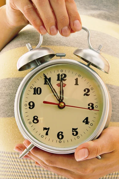 Young pregnant woman with alarm clock — Stock Photo, Image