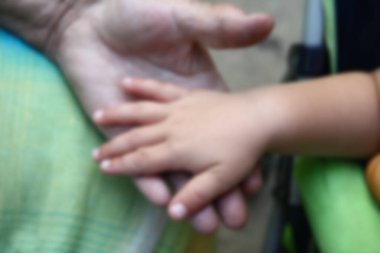 Yaşlı bulanık büyükannelerin elleri genç torunun ellerini tutar.