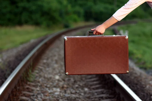 hand of young woman with a suitcase near railway