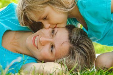 Anne ile çocuk parkta çimlerin üzerinde oynuyorlar.