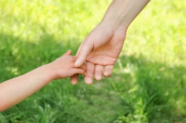 Mutlu bir geçmişi olan çocuğun elini tutan ebeveyn.