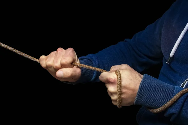 Hands with a rope on a black background. A man pulls a rope wrestling. Drag the business to your side.