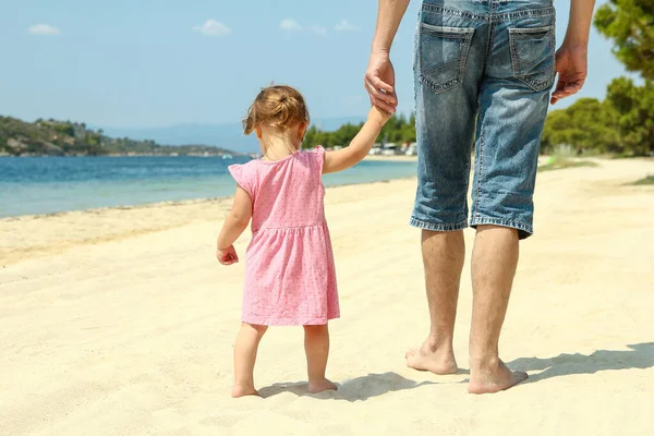 親は海の近くのビーチで小さな子供の手を握っていて — ストック写真