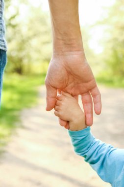Mutlu bir geçmişi olan çocuğun elini tutan ebeveyn.
