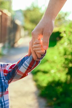 Mutlu bir geçmişi olan çocuğun elini tutan ebeveyn.