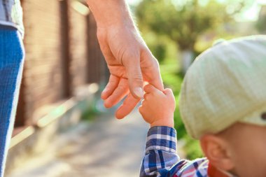Mutlu bir geçmişi olan çocuğun elini tutan ebeveyn.