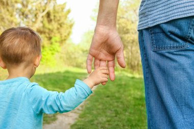Mutlu bir geçmişi olan çocuğun elini tutan ebeveyn.