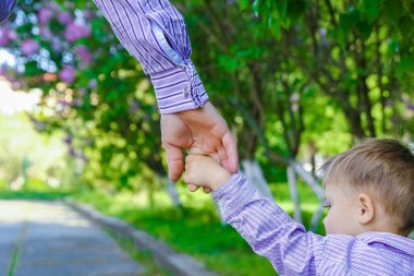 Mutlu bir geçmişi olan çocuğun elini tutan ebeveyn.