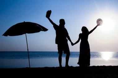 Gün batımında deniz kenarında mutlu bir çift doğada gezici bir siluette