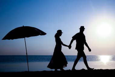 Gün batımında deniz kenarında mutlu bir çift doğada gezici bir siluette