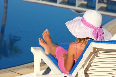 Havuz kenarında güneşlenen güzel bir kız.