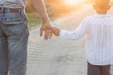 Yolun kenarındaki parkta mutlu bir çocuk ve ebeveynin elleri.