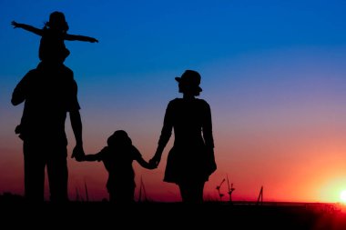 Gün batımında deniz kenarında mutlu bir aile doğada gezici bir siluette