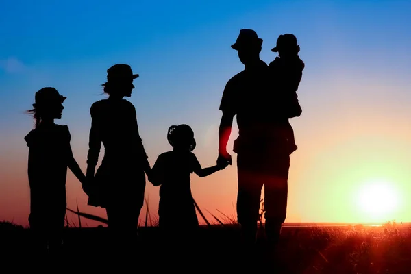 自然の中で旅行のシルエットで日没で海によって幸せな家族 — ストック写真