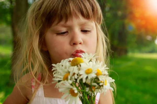 自然公園で花の花束を持つ舌の幸せな女の子の子供を示す子供の感情 — ストック写真