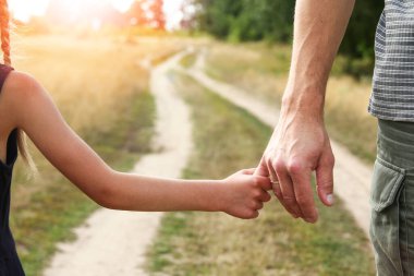 Ebeveyn, doğada küçük bir çocuğun elini tutar.