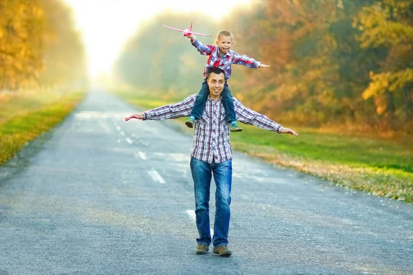 幸せな親は 自然旅行で公園内の子供と飛行機と一緒に道路に沿って歩く — ストック写真