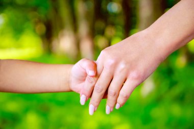 Mutlu aile ve çocuk parkta el ele tutuşuyor.