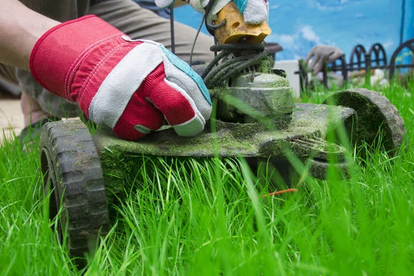 a man mows the grass with a trimmer in garden