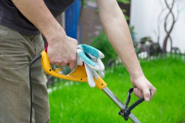 Bir adam bahçede çimleri biçiyor.