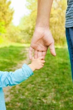 Mutlu bir geçmişi olan çocuğun elini tutan ebeveyn.