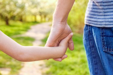 Mutlu bir geçmişi olan çocuğun elini tutan ebeveyn.