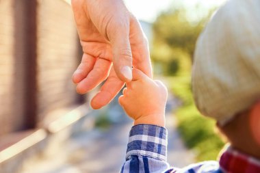 Mutlu bir geçmişi olan çocuğun elini tutan ebeveyn.