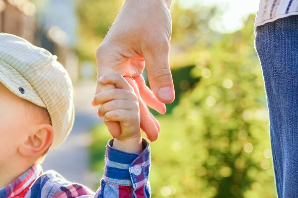 幸せな背景を持つ子供の手を握っている親は — ストック写真