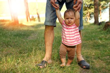 Ebeveyn, doğa destek konseptinde küçük bir çocuğun elini tutuyor.