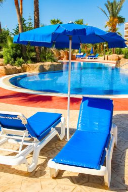 Deniz zeminine yakın havuz kenarında güneşli yataklar.