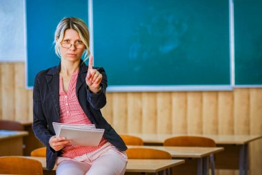 Sınıfta kitapları olan mutlu bir öğretmen okula geri döndü.