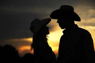 Silhouette of couple in cowboy hats clipart