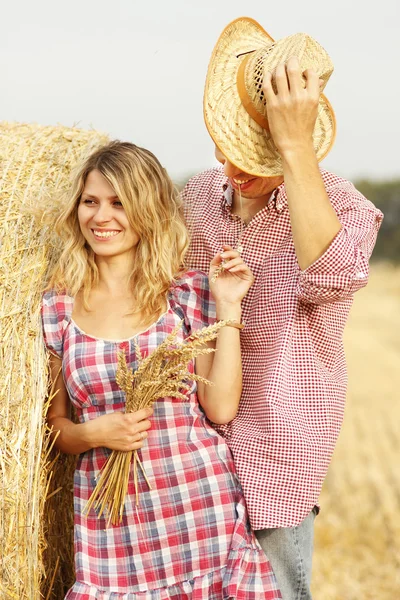 Couple near haystack in cowboy hats — Stock Photo, Image