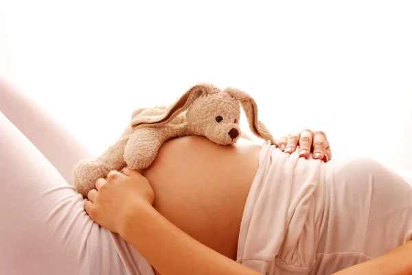 Беременная женщина с плюшевой игрушкой — стоковое фото