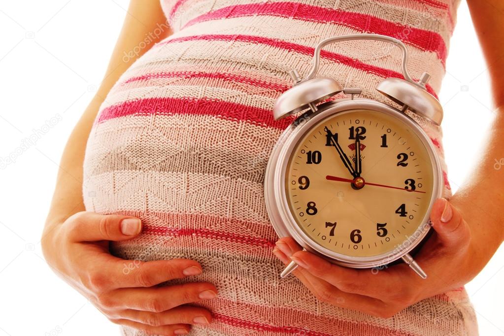 Pregnant woman holding clock