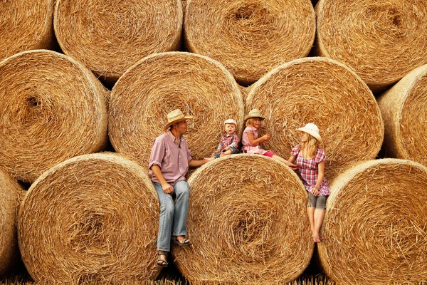 Family sitting on haystacks in cowboy hats — Stock Photo, Image