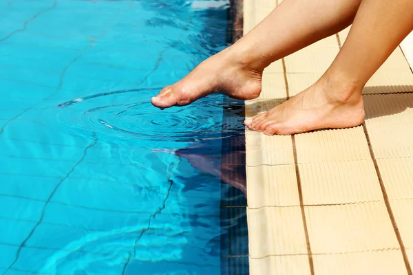 Jambes féminines au bord de la piscine — Photo