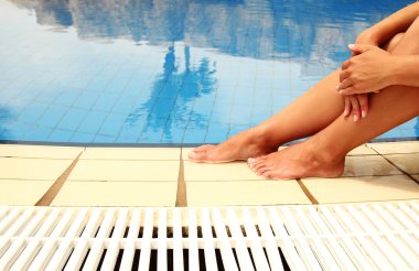 Havuz suyu üzerinde kadın bacakları