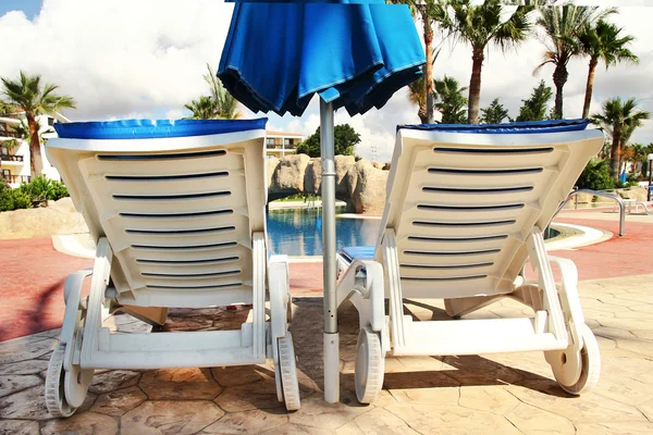 Camas de sol e guarda-sóis sobre a piscina — Fotografia de Stock