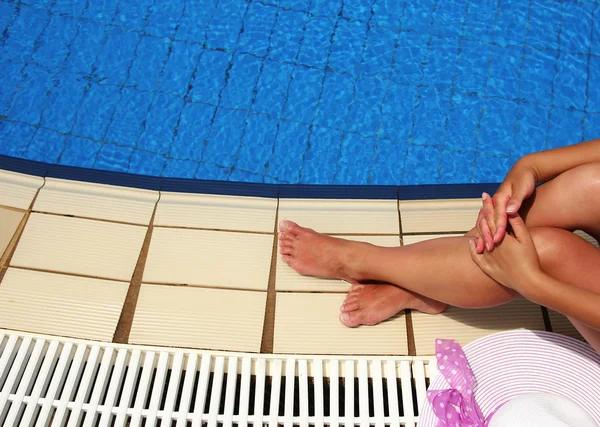 Piernas femeninas sobre el agua de la piscina — Foto de Stock