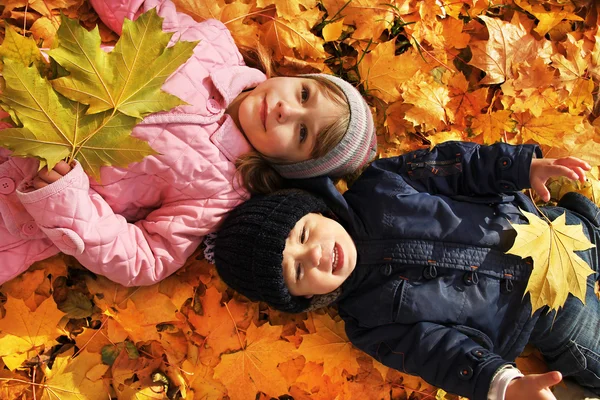 Niños acostados en hojas de otoño — Foto de Stock