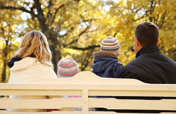 Familjen sitter på bänken i park — Stockfoto