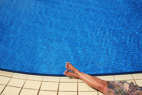 Pernas femininas na água da piscina — Fotografia de Stock