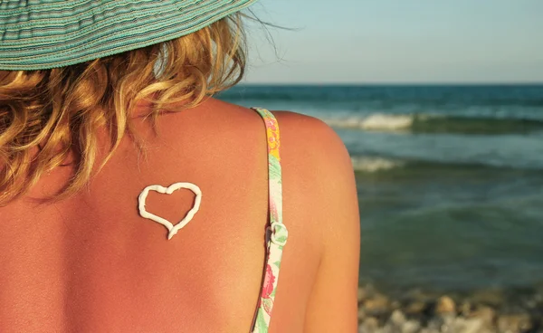 Corazón de crema solar en la espalda femenina —  Fotos de Stock