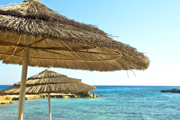 Beach umbrellas on sea shore — Stock Photo, Image