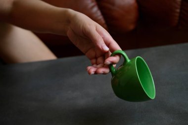 Yeşil bir kupa. Bir kadın elinde yeşil bir kupa tutuyor..