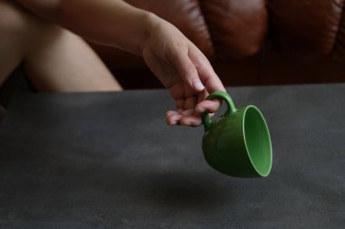 Yeşil bir kupa. Bir kadın elinde yeşil bir kupa tutuyor..