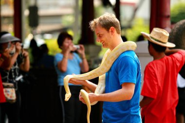 Ocak 2010 Pattaya, Tayland: Avrupalı genç bir turist boynunda sarı bir yılanla kameraya poz veriyor.