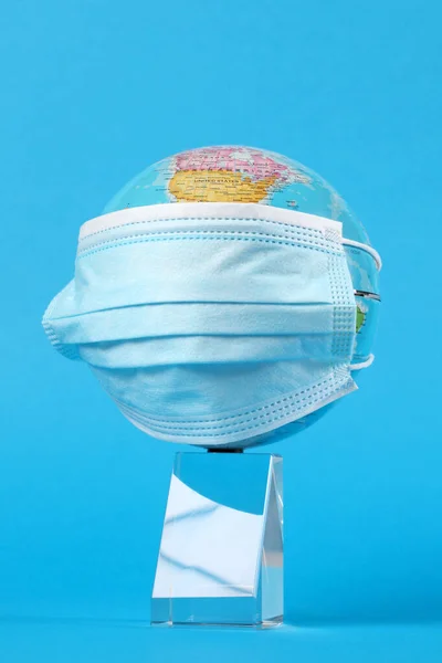 medical face mask cover a globe on light blue background with copy space for your text