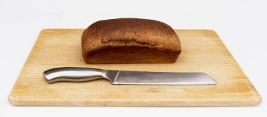 Sağlıklı bir somun taze ev yapımı, fırınlanmış ekmeği doğrama tahtasının üzerinde, kesmeye hazır bir bıçakla bekliyor..